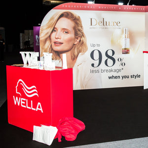 Red branded retail display counter with lockable doors on a Wella exhibition stand